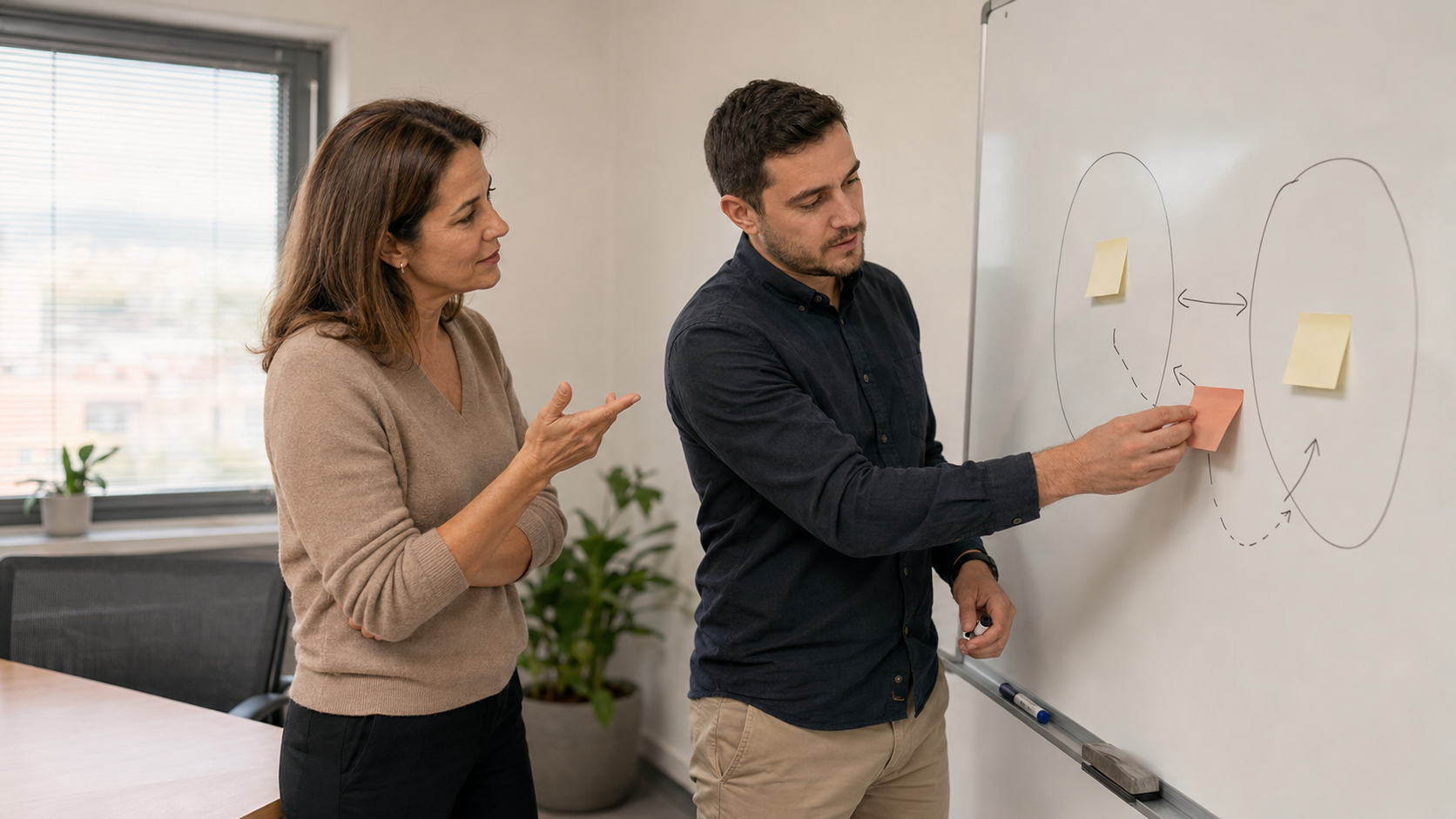 Two colleagues working through a diagram on a whiteboard during a leadership coaching session.